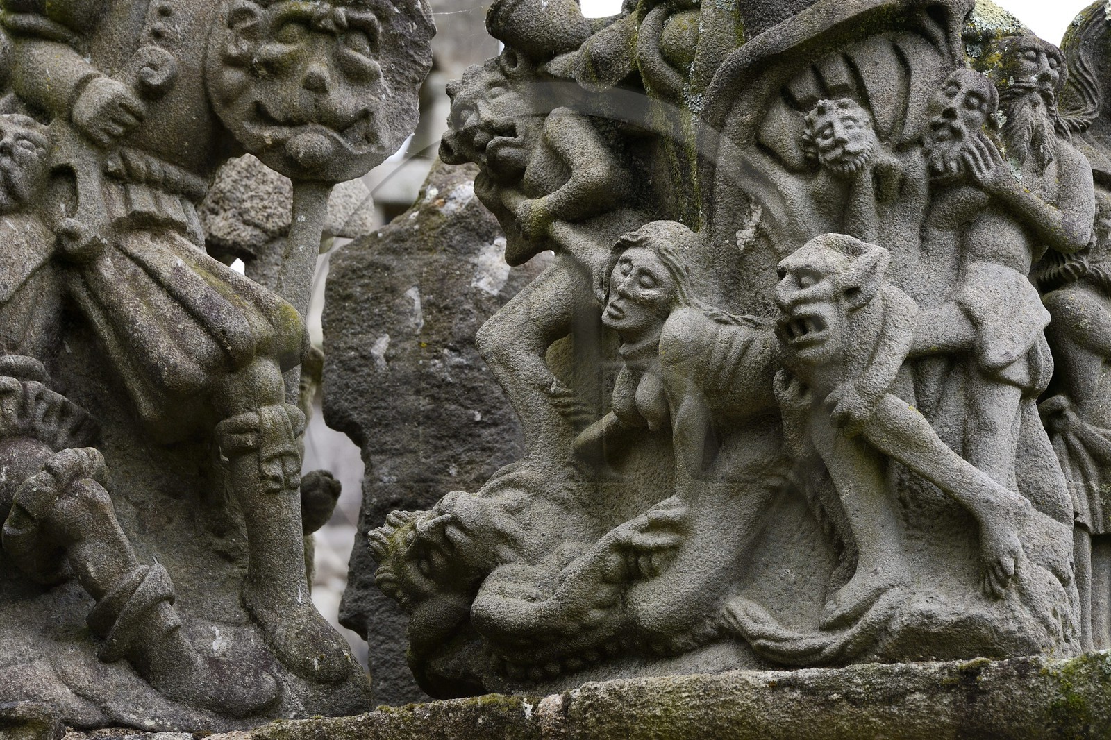 France, Finistère (29), Guimiliau, le calvaire dans l'enclos paroissial, selon la légende la jeune servante katell Gollet est vouée au flammes éternelles car elle aurait dissimulé ses écarts de conduite en confession et commis le sacrilège de dérober une hostie consacrée qu'elle a offerte à Satan qui se cachait sous les traits de son amant