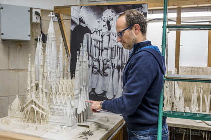 Spain, Catalonia, Barcelona, Eixample district, Sagrada Familia basilica by Catalan modernist architect Antoni Gaudi, listed as a UNESCO World Heritage Site, the model workshop, Architect and coordinator of the team of artists and model makers Jeronimo Buxareu Padros presents the next works to be undertaken, the future Glory facade in front of him and the photo of the original Gaudi model in the background