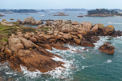 France, Cotes-d'Armor, Cote de Granit Rose, Perros-Guirec, Ploumanac'h, rocks at the Pointe de Skewell (Squéouel) on the Douaniers trail also GR 34 long-distance trail and the castle of Costaérès on its island in the background (aerial view)