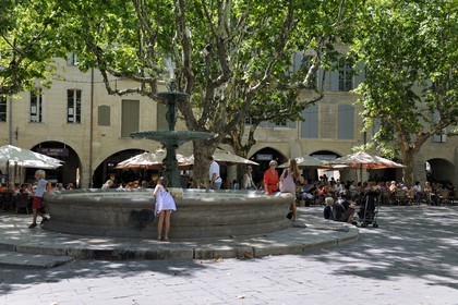 France, Gard, Uzes, listed as town of art and history, fountain of the Place aux Herbes surrounded by arcaded houses and its outdoor cafes