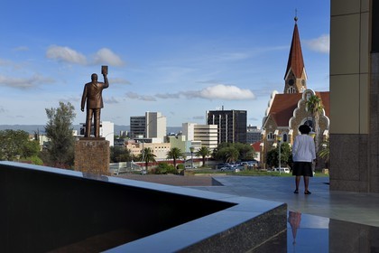 Namibie, région de Khomas, Windhoek, Christ Church (or Christuskirche), l'église luthérienne dessinée par l'architecte Gottlieb Redecker vue depuis le Independence Memorial Museum construit par la Corée du Nord et statue du Dr Sam Nujoma (président fondateur de la nation namibienne)