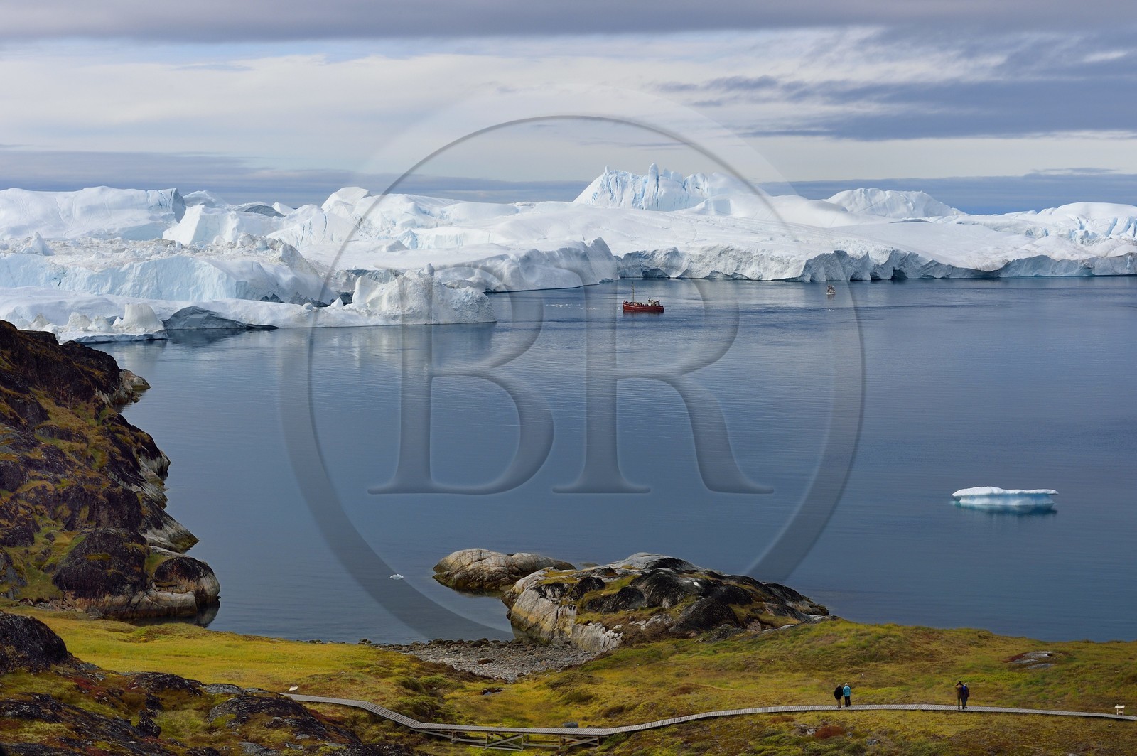 Groenland, cote ouest, baie de Disko, Ilulissat, fjord glacé classé Patrimoine Mondial de l'UNESCO qui est l’embouchure maritime du glacier Sermeq Kujalleq (Jakobshavn Glacier), passerelle en bois du chemin de randonnée allant sur le site de Sermermiut et bateau de pêche au pied des icebergs