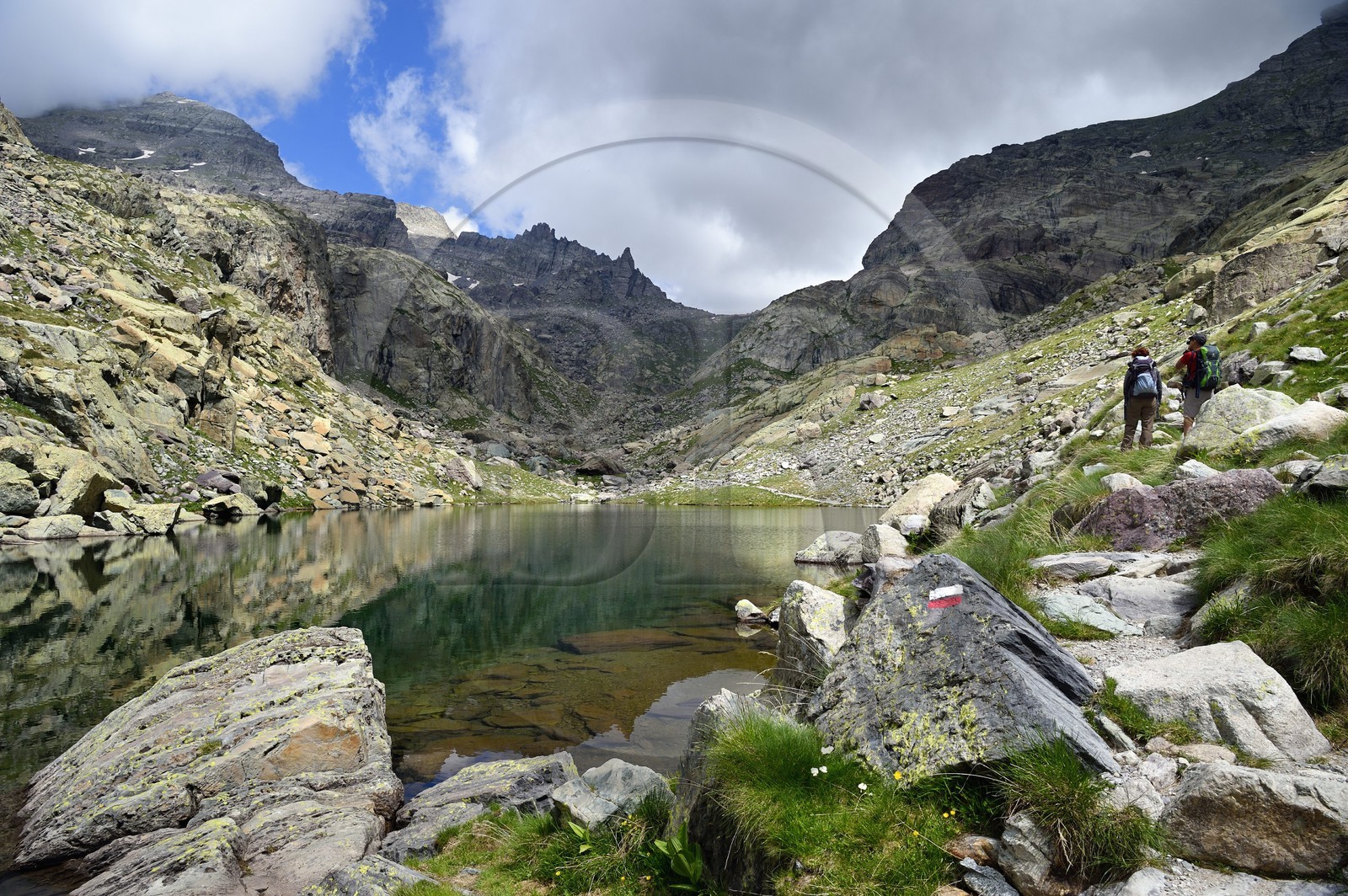 France, Alpes-Maritimes, parc national du Mercantour (Mercantour National Park), the Vallee des Merveilles (Valley of Wonders) scattered with thousands of rupestral engravings of the Bronze Age, hikers on the trail GR 52 at the Merveilles Lake below the Baisse (pass) de Valmasque and the Mont Grand Capelet (2915 m) in the background left