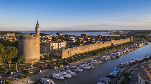 France, Gard, Aigues Mortes, the medieval town surrounded by its ramparts, the Tower of Constance and the port of the Rhone to Sète Canal in the foreground, the salt marshes (Salins du Midi) in the background (aerial view)