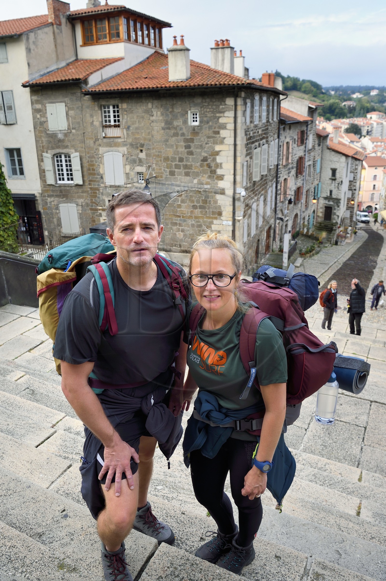 France, Haute-Loire (43), Le Puy-en-Velay, un couple de pélerins en partance sur le chemin de Compostelle sur les escaliers du porche de la cathédrale Notre-Dame-de-l'Annonciation du XIIe siècle classée Patrimoine Mondial de l'UNESCO