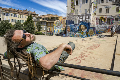 France, Bouches-du-Rhône (13), Marseille, quartier du Panier, peintures murales et graffitis place du Refuge, le street artiste Loïc Perrel dit Poasson pose devant la fresque de l'enfant footbaleur et de la femme qu'il a réalisé en arrière plan