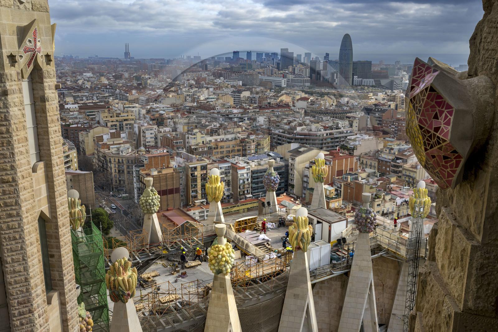 Espagne, Catalogne, Barcelone, quartier de l'Eixample, basilique de la Sagrada Familia de l'architecte du modernisme catalan Antoni Gaudi classée Patrimoine Mondial de l'UNESCO, sommets surmontés de mosaïques en forme de fruits entourant le chantier sur le toit de la nef à l'arrière de la future facade de la Gloire, la Torre Agbar de l'architecte Jean Nouvel en arrière plan