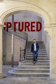 France, Vaucluse (84), Avignon, Collection Lambert, Musée d'Art Contemporain, aménagé dans les hôtels particuliers de Caumont et de Montfaucon du XVIIIe siècle, Stéphane Ibars, directeur artistique de la Collection descend l'escalier sous Ruptured (1970) de l'artiste Lawrence Weiner