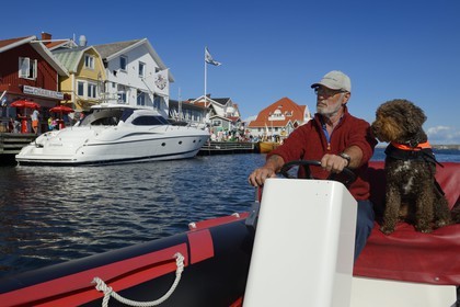 Sweden, Västra Götaland, Smögen harbour, Cyril and his dog Simpson aboard his zodiac
