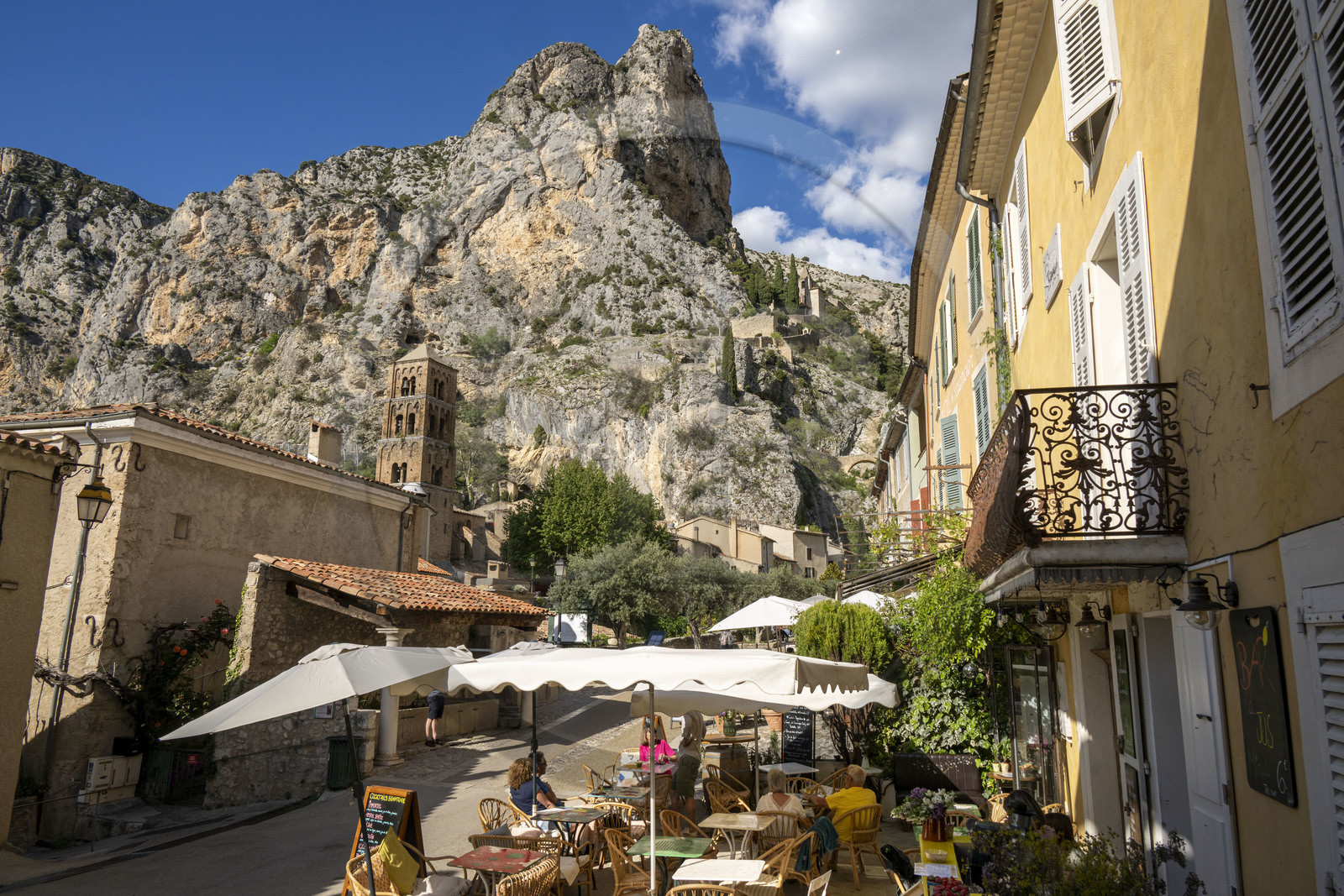 France, Alpes-de-Haute-Provence (04), Parc Naturel Régional du Verdon, Moustiers-Sainte-Marie, labellisé Les Plus Beaux Villages de France, l'église Notre-Dame-de-l'Assomption avec son clocher du XIIe siècle en tuff et l'Etoile de Moustier accrochée à une chaîne à plusieurs dizaines de mètres au-dessus du sol, la chapelle Notre-Dame de Beauvoir en arrière plan dans la falaise