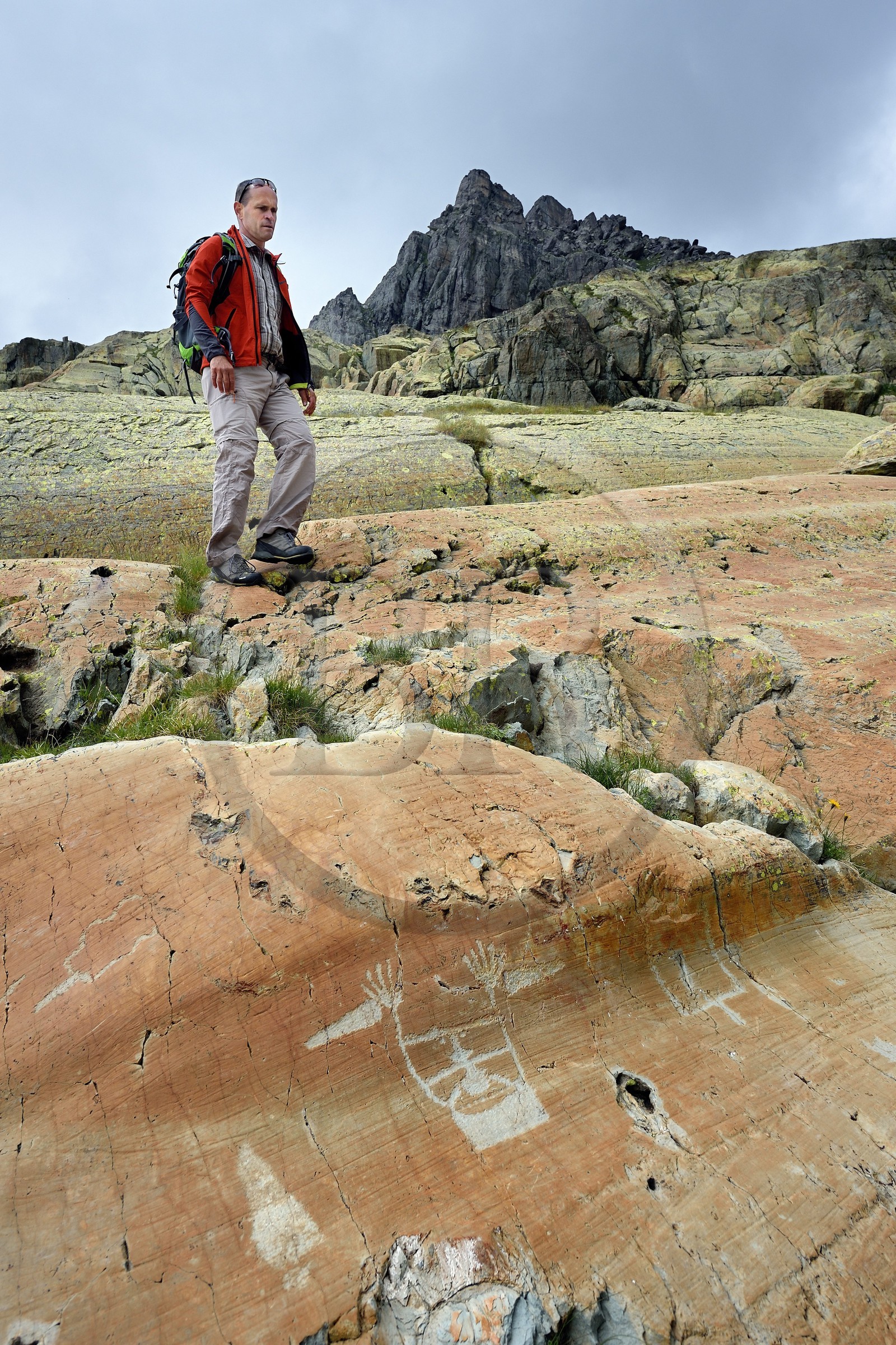 France, Alpes-Maritimes (06), parc national du Mercantour, vallée des Merveilles parsemée de milliers de gravures rupestres de l'Age de bronze, randonneur au dessus de la figure anthropomorphe gravée sur la roche dite du Sorcier sur les dalles de schiste jaune des chiappes