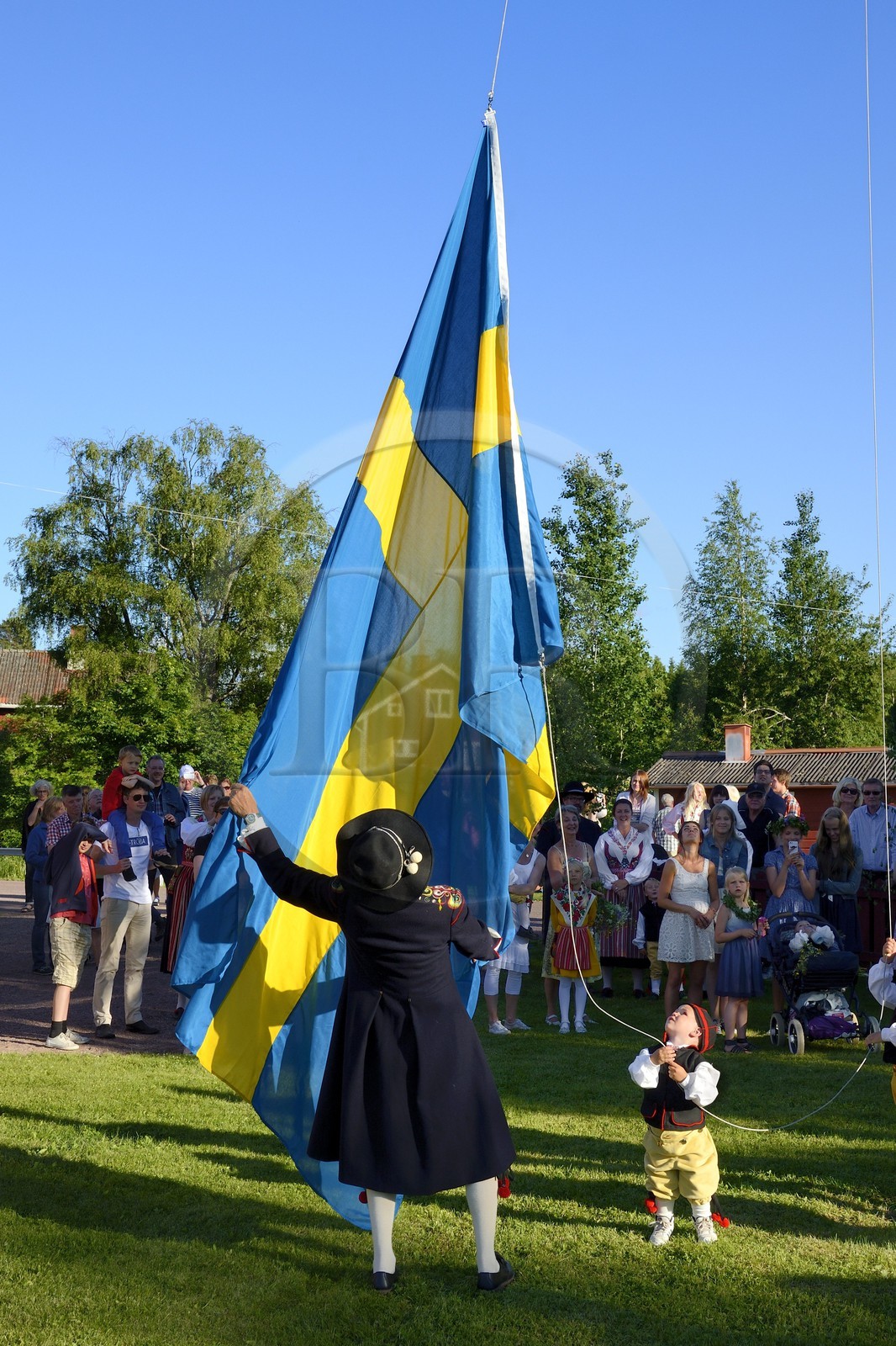 Sweden, Dalarna County, Leksand area, Midsummer celebrations in the tiny hamlet of Hjulbäck, raising the Swedish flag
