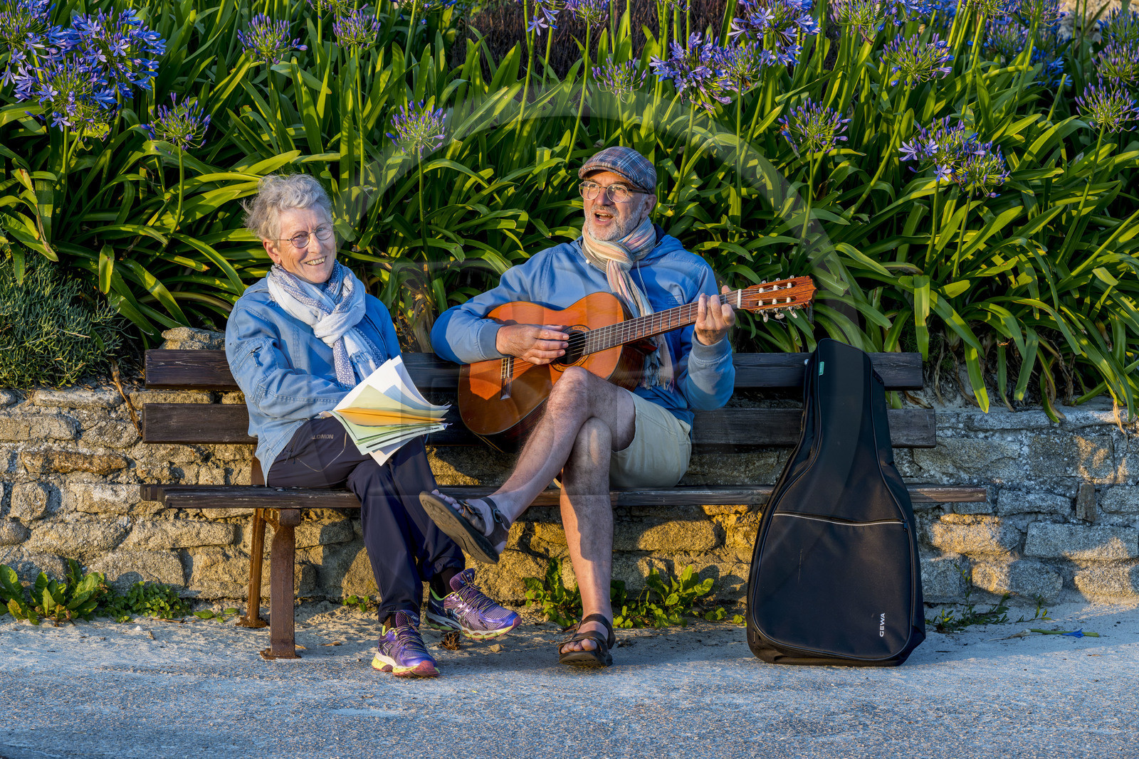 France, Finistère (29), Iles du Ponant, Ile de Batz, Remi joue de la guitare pour Françoise sur un banc de l'embarquadère en fin de journée