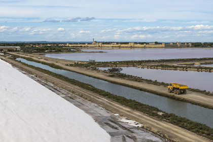 France, Gard, Aigues Mortes, the medieval town surrounded by its ramparts on the edge of the salt marshes (Salins du Midi) from a mountain of stored salt