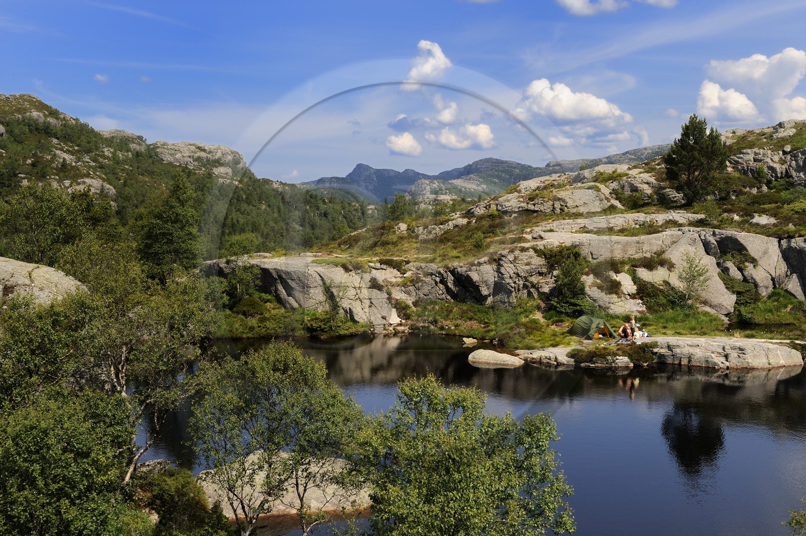 Norway, Rogaland County, around Lysefjord, campers on the edges of a small lake on the hiking trail leading to Preikestolen Rock
