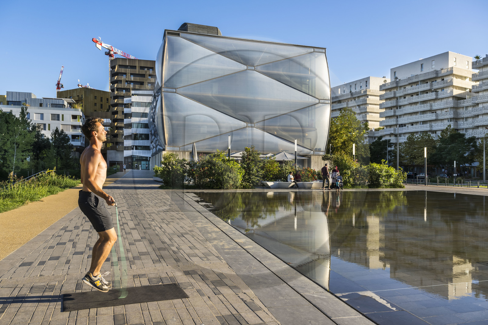 France, Herault, Montpellier, Port Marianne district, Le Nuage building by designer Philippe Starck, sportsman jumping rope in front of the water mirror in the foreground on avenue Raymond Dugrand