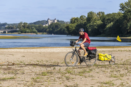 France, Maine-et-Loire (49), vallée de la Loire classée au Patrimoine Mondial par l'UNESCO, Saumur vers Saint-Hilaire, bancs de sable formant des îles sur la Loire et le chateau de Saumur en arrière plan, randonnée à bicyclette sur les berges de la Loire, vélo avec une remorque transportant le matériel de camping