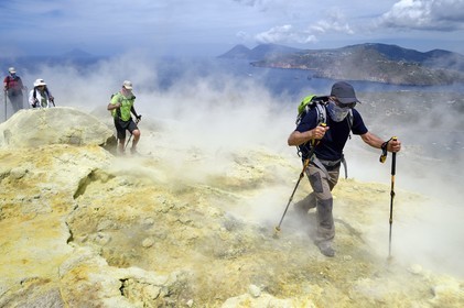 Italy, Sicily, Aeolian Islands, listed as World Heritage by UNESCO, Vulcano Island, hikers climbing the crater of volcano della Fossa through sulfur fumaroles, the island of Lipari then Salina island in the background