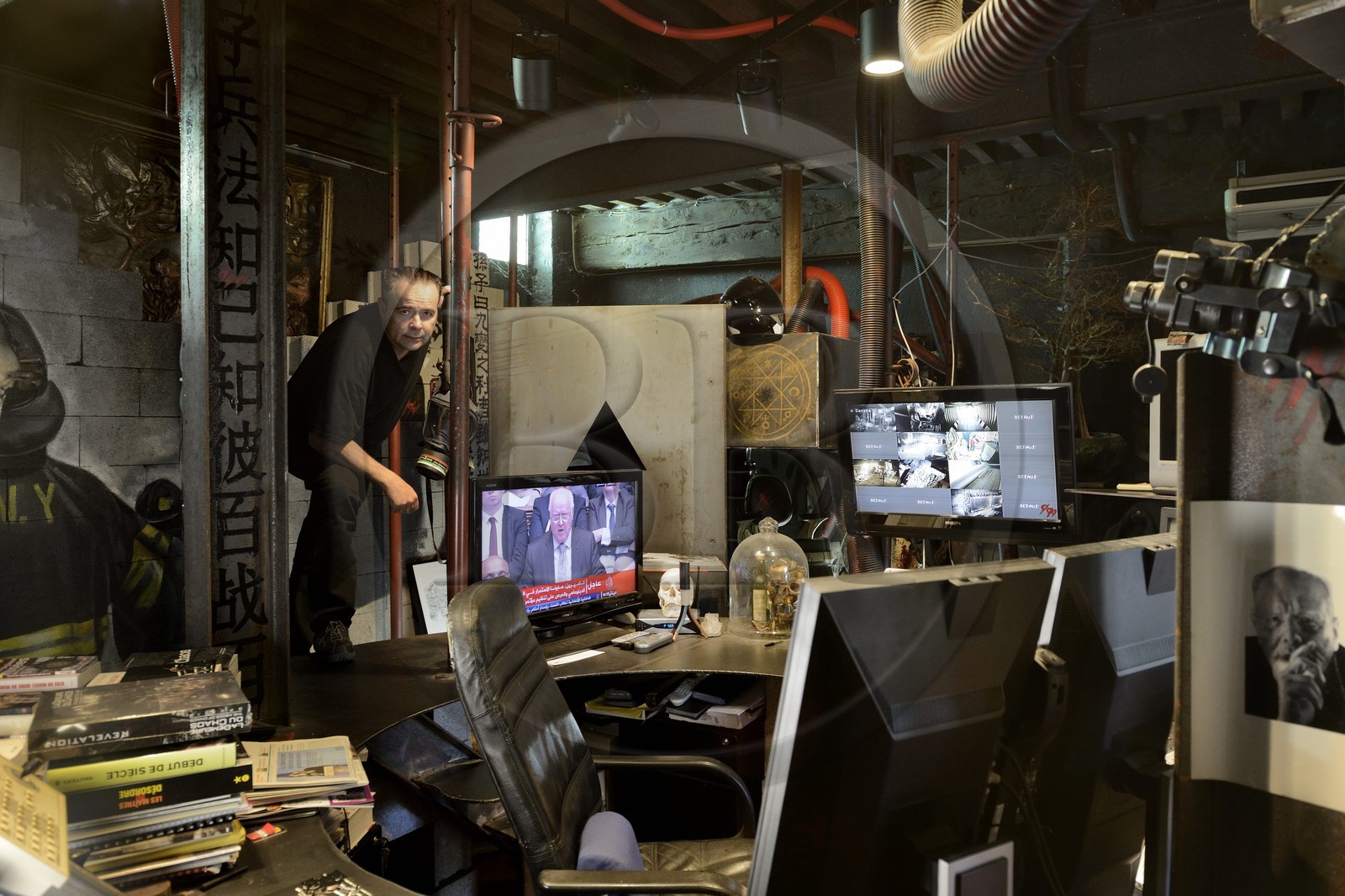 France, Rhône (69), Saint-Romain-au-Mont-d'Or, la Demeure du Chaos, l'œuvre d'art est basé sur la transformation sans fin de la maison du XVIIème siècle de l'artiste plasticien Thierry Ehrmann en une réplique de zone de guerre à l'image du monde présent, portrait de Thierry Ehrmann, aussi président fondateur de Artprice et du Groupe Serveur, sur son bureau