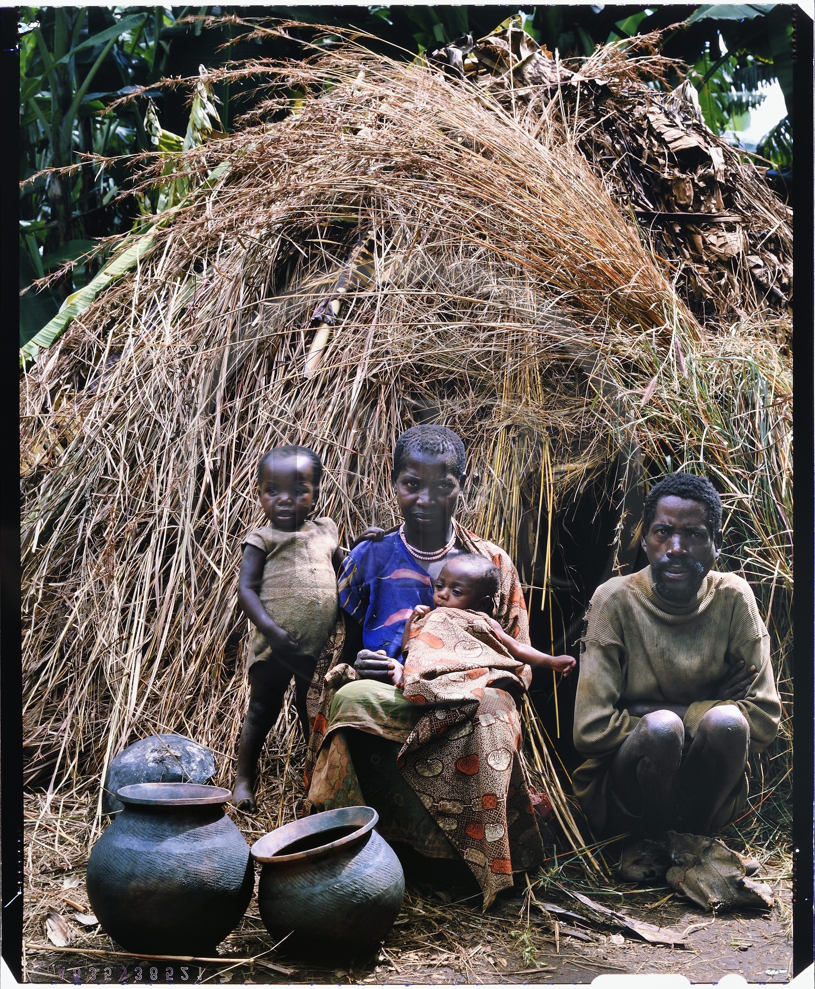 Burundi, province de Muyinga, potiers Twa ou Batwa (pygmées), leur habitat est généralement très pauvre comme ici des cases en paille, les pots (inkono) en argile sont modelés à la main sur un tesson de vieux pot par la technique du colombin, après être lissé, un dessin est imprimé à l'aide d'un bâtonnet ou d'une cordelette tressée qu'on fait rouler sur la surface du pot, lorsque les pots sont secs au bout de plusieurs jours, ils sont sommairement cuits dans un feu de branchages et d'herbes mais les cendres de la cuisson doivent apparaître lors de la vente afin de prouver que le pot n'a jamais été utilisé par les Twa car personne n'en voudrait (reproduction plan-film inversible 4x5)