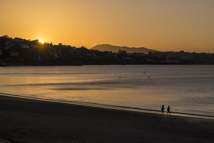 France, Pyrenees Atlantiques, Basque Country, Saint Jean de Luz, walkers on the Grande Plage and the coast of Ciboure in the bay in the background