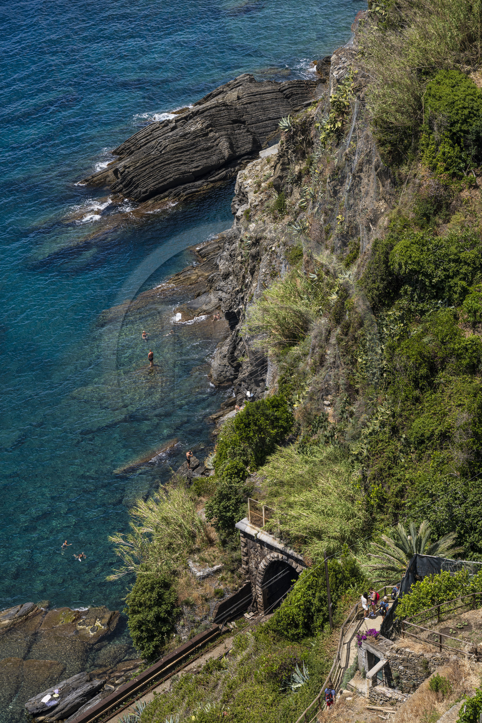 Italie, Ligurie, Cinque Terre, parc national des Cinque Terre classé Patrimoine Mondial de l'UNESCO, village de Vernazza, randonneurs sur le sentier du littoral GR 592 surplombant la voie de chemin de fer et les baigneurs au pied des falaises