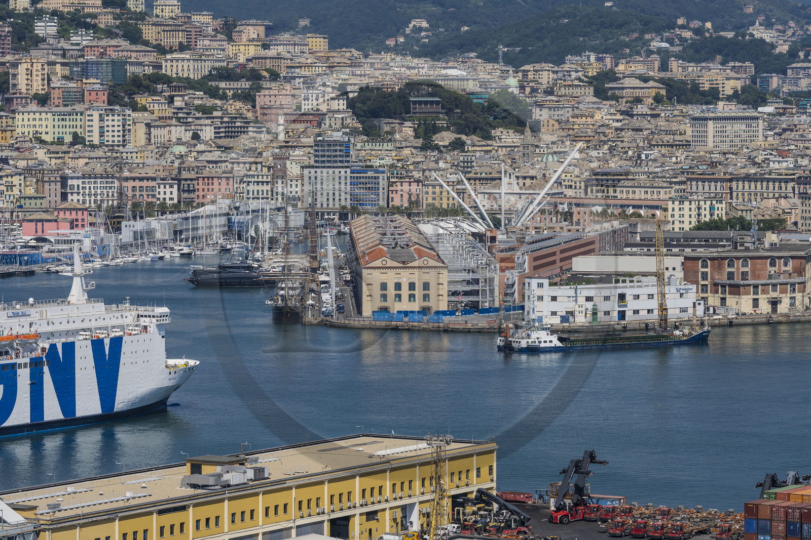 Italy, Liguria, Genoa, the container terminal of the commercial port and the Porto Antico (Old Port) on the edge of the city in the background