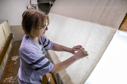 France, Vaucluse (84), L'Isle-sur-la-Sorgue, Manufacture Brun de Vian-Tiran, industrie textile lainière labellisée Entreprise du patrimoine vivant, atelier d'épincetage, ouvrière entrain d'enlever du tissus les défauts à la pince