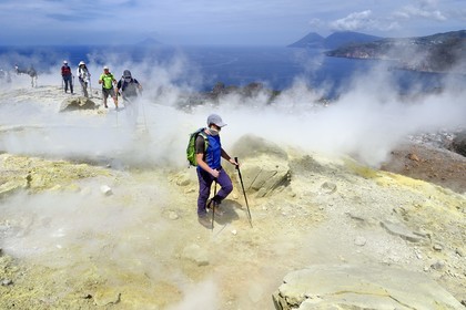 Italie, Sicile, iles Eoliennes, classées Patrimoine Mondial de l'UNESCO, ile de Vulcano, randonneurs dans l'ascension du cratère du volcan della Fossa à travers les fumerolles soufrées, l'Ile de Lipari puis Ile de Salina en arrière plan