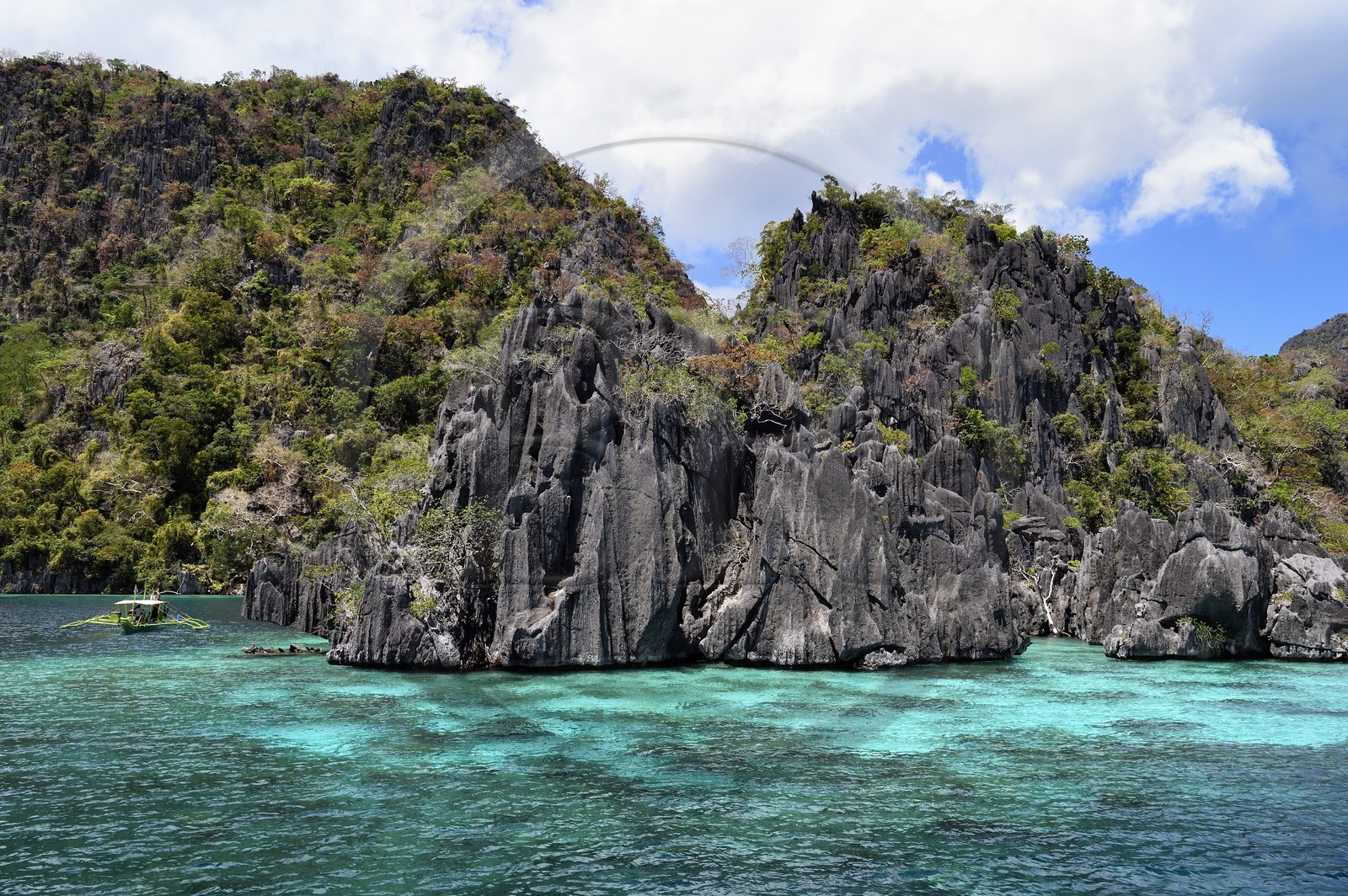Philippines, Calamian Islands dans le nord de Palawan, Coron Island Natural Biotic Area, pirogue à balancier dans un lagon au pied des falaises de calcaire du Permien d'origine jurassique