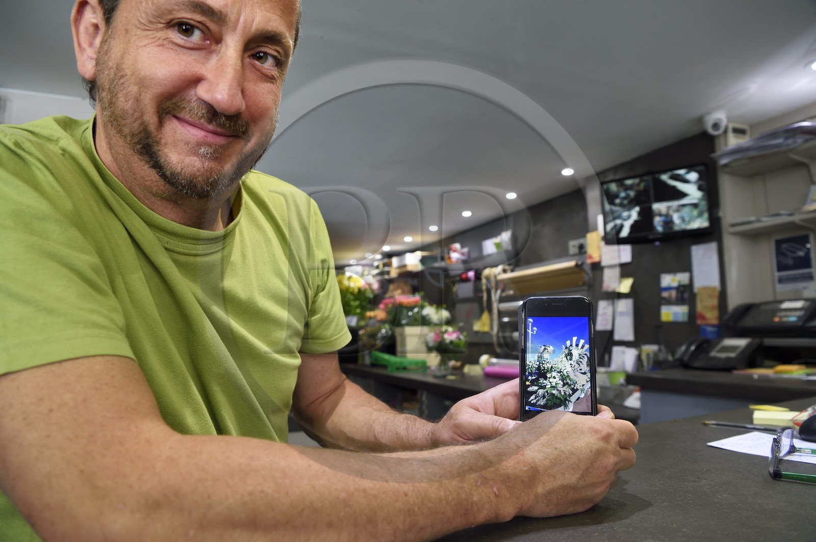 France, Alpes-Maritimes (06), Nice, le fleuriste Joseph Pinna dans sa boutique Arc en ciel fleurs rue Barberis, il nous montre un char qu'il a décoré pour le carnaval sur son écran de téléphone