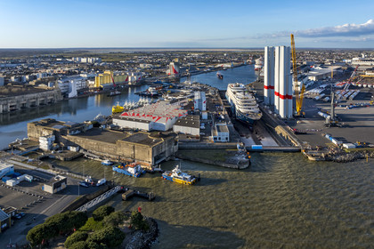 France, Loire-Atlantique (44), Saint-Nazaire, l’écluse Est et l'écluse fortifiée de l'ancienne base sous-marine allemande construite lors de la dernière guerre mondiale au premier plan et le chantier du super-yacht de luxe Ritz-Carlton Luminara dans la forme Joubert, les tours d'éoliennes à droite sont stockées avant embarquement (vue aérienne)