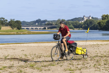 France, Maine-et-Loire (49), vallée de la Loire classée au Patrimoine Mondial par l'UNESCO, Saumur vers Saint-Hilaire, bancs de sable formant des îles sur la Loire et le chateau de Saumur en arrière plan, randonnée à bicyclette sur les berges de la Loire, vélo avec une remorque transportant le matériel de camping