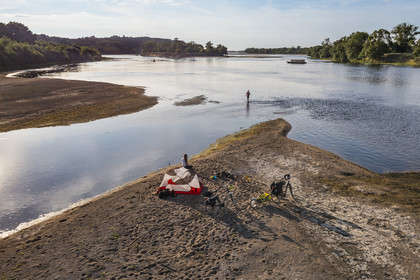 France, Maine-et-Loire (49), vallée de la Loire classée au Patrimoine Mondial par l'UNESCO, randonnée à bicyclette le long des berges de la Loire, campement pour la nuit sur un des bancs de sable formant des îles sur la Loire, une gabarre (bateau traditionnel à fond plat) en arrière plan (vue aérienne)