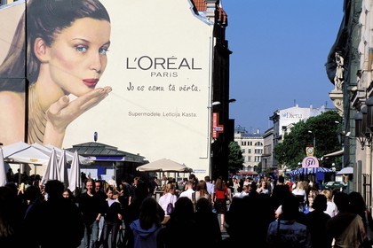 Lettonie (Pays Baltes), Riga, piétons sur la place jouxtant rue Kalku peinture murale publicitaire avec le top model Laetitia Casta (L'Oréal)