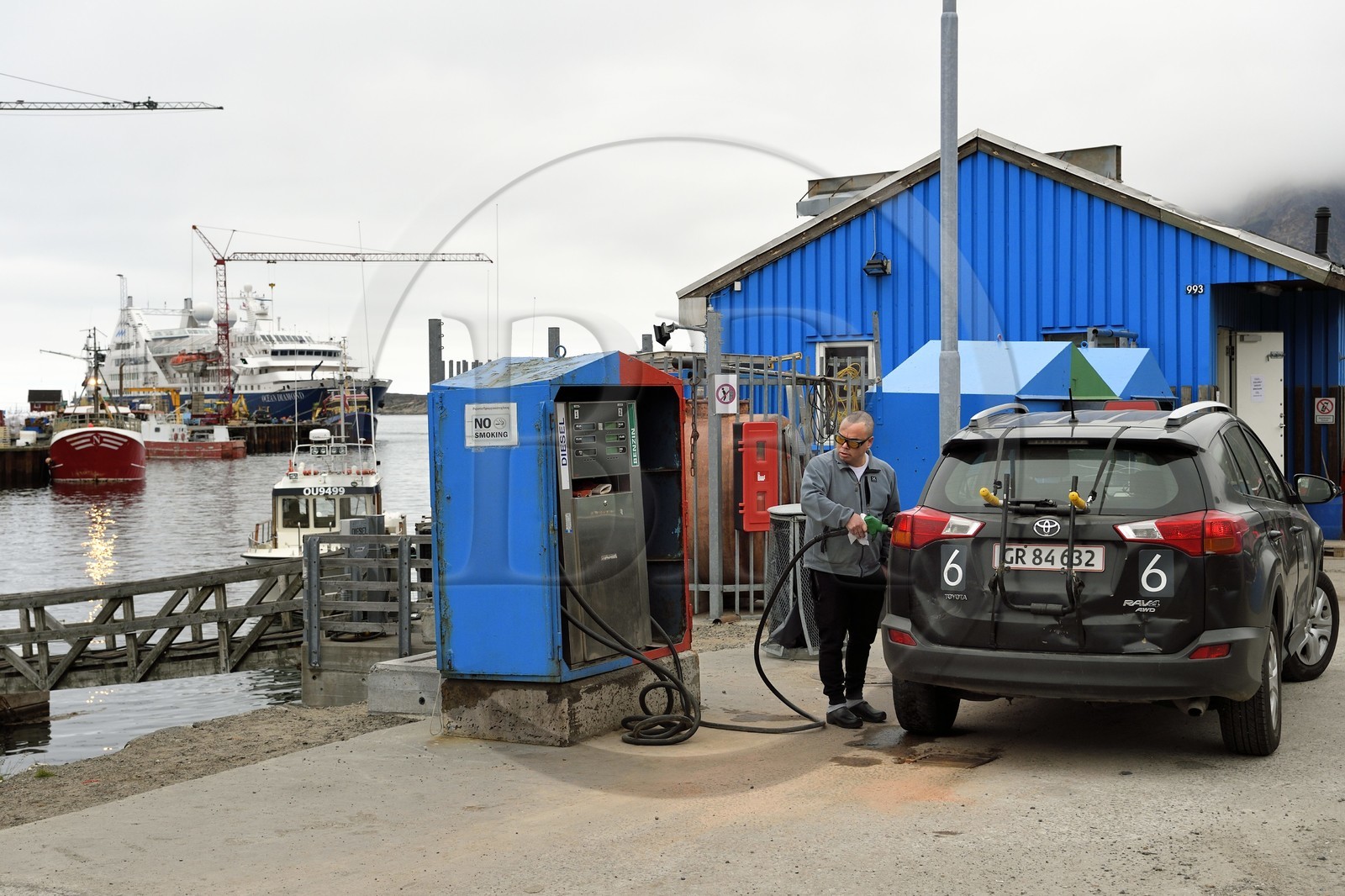 Groenland, région du centre ouest, Sisimiut (autrefois Holsteinsborg), homme remplissant le réservoir d'essence de sa voiture à la station-service sur le port