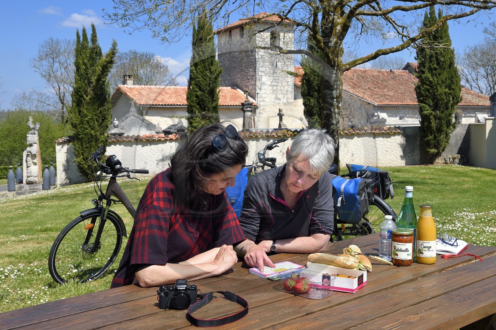 France, Charente, Souffrignac, picnic for cyclists on the Flow Vélo cycle route at the Jardins du Bandiat, the 12th century Romanesque church of Saint-Antoine in the background