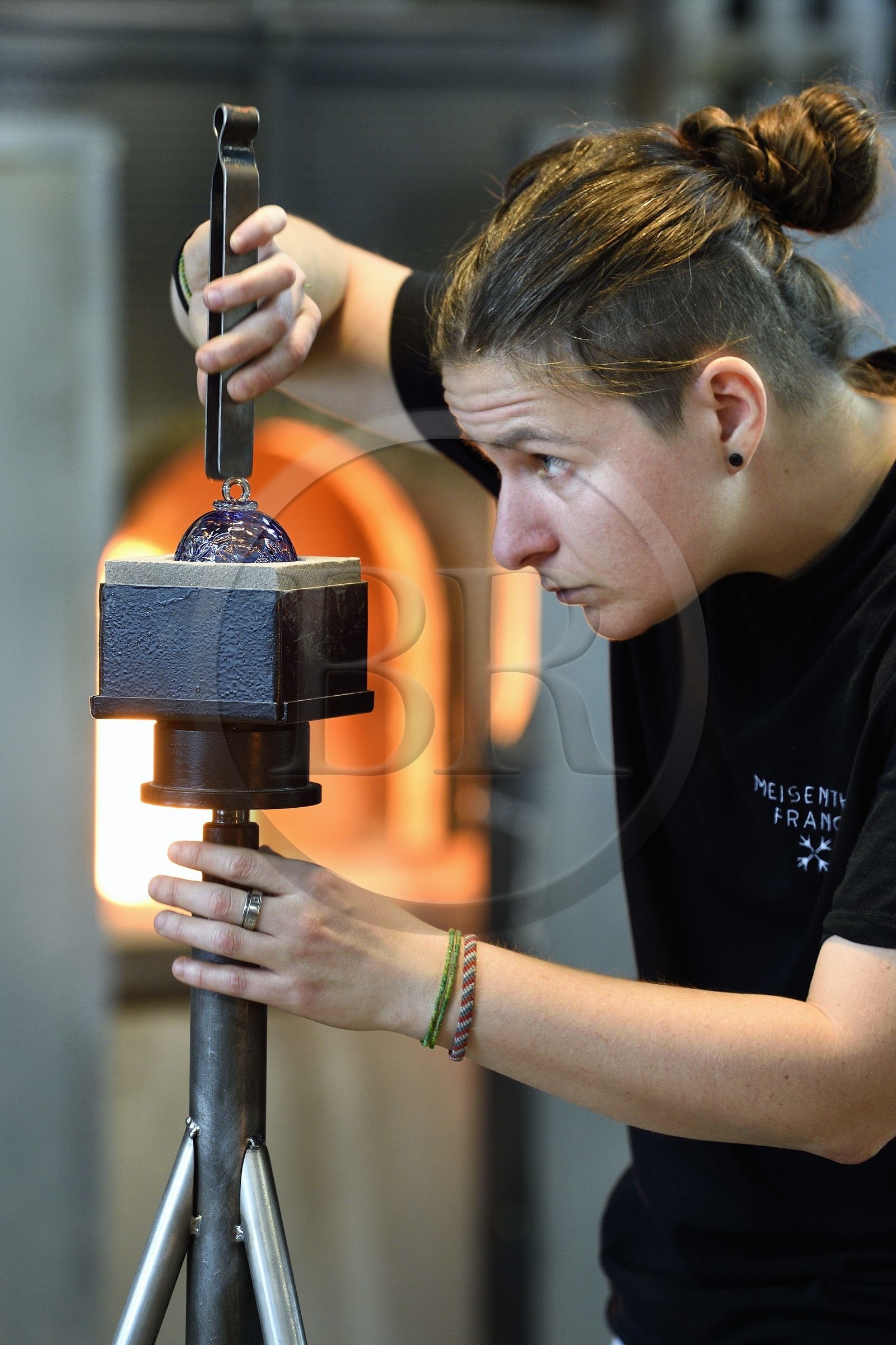 France, Moselle (57), Meisenthal, Centre international d’Art verrier (CIAV), l'atelier de soufflage, fabrication artisanale d'une boule de Noël, finalisation de la mise en place du crochet en verre