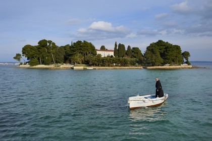 Croatia, Dalmatia, Dalmatian Coast, Ugljan Island, Preko, Franciscan friar Bozo Susic leaving the Franciscan Monastery of the Galovac island on his boat