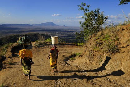 Tanzanie, région de Morogoro, les Monts Uluguru, aux alentours de l'ancien refuge allemand de Morningside, femmes avec un bébé dans le dos portant leurs provisions sur la tête, dans la plaine on aperçoit la ville de Morogoro