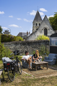 France, Maine-et-Loire (49), vallée de la Loire classée au Patrimoine Mondial par l'UNESCO, Gennes-Val-de-Loire, randonnée à bicyclette sur les berges de la Loire, pause à la librairie-café L'Idiot de l'association Gabare And Co dans l'ancienne école des Filles de Chênehutte, l'église notre dame des tuffeaux en arrière plan