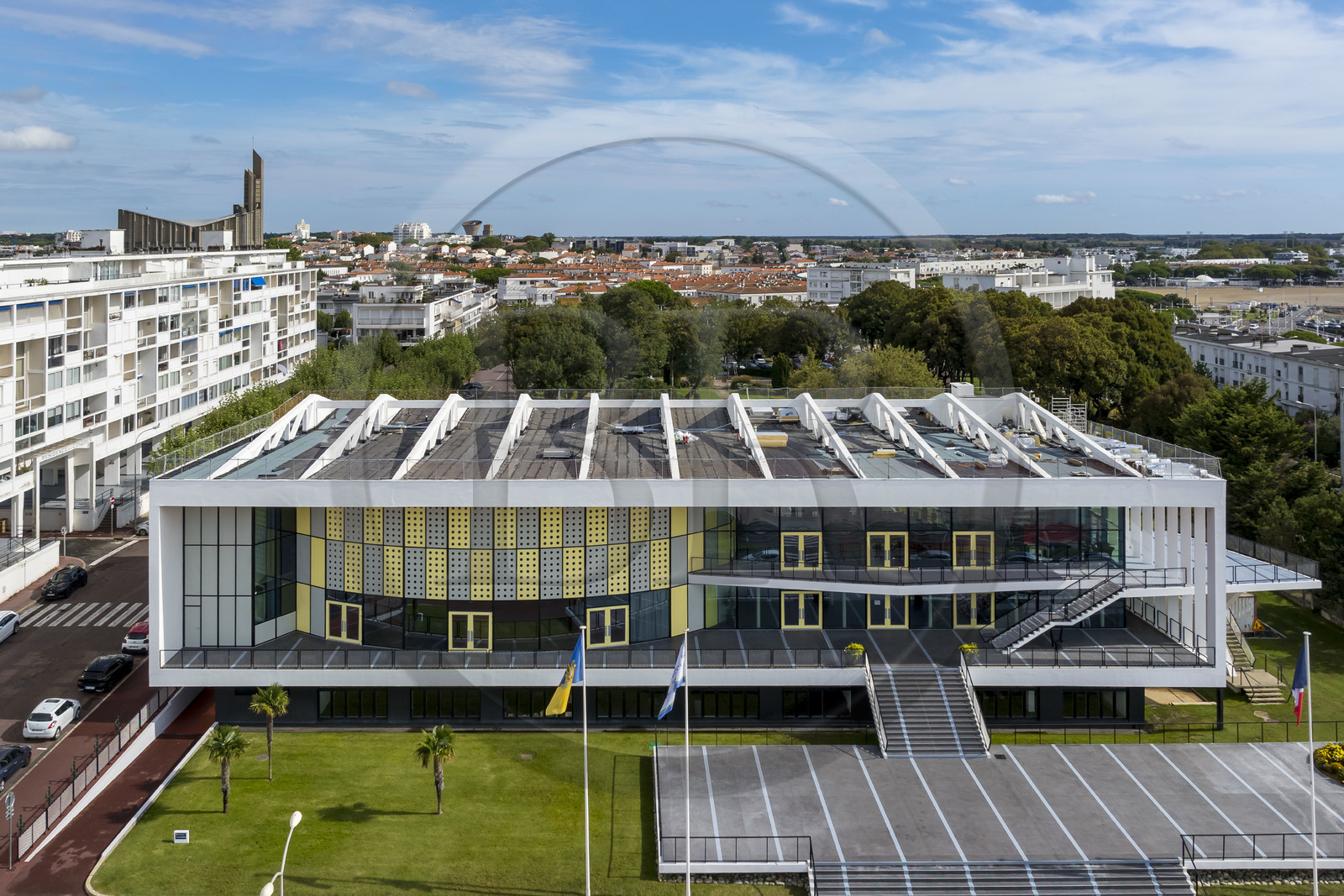 France, Charente-Maritime (17), Royan, le Palais de congrès (1957) signé de l’architecte-urbaniste Claude Ferret et rythmés par les panneaux perforés en aluminium jaune et gris des ateliers Jean Prouvé en façade, l'église Notre-Dame de Royan construite de 1955 à 1958 par l'architecte Guillaume Gillet en arrière plan (vue aérienne)