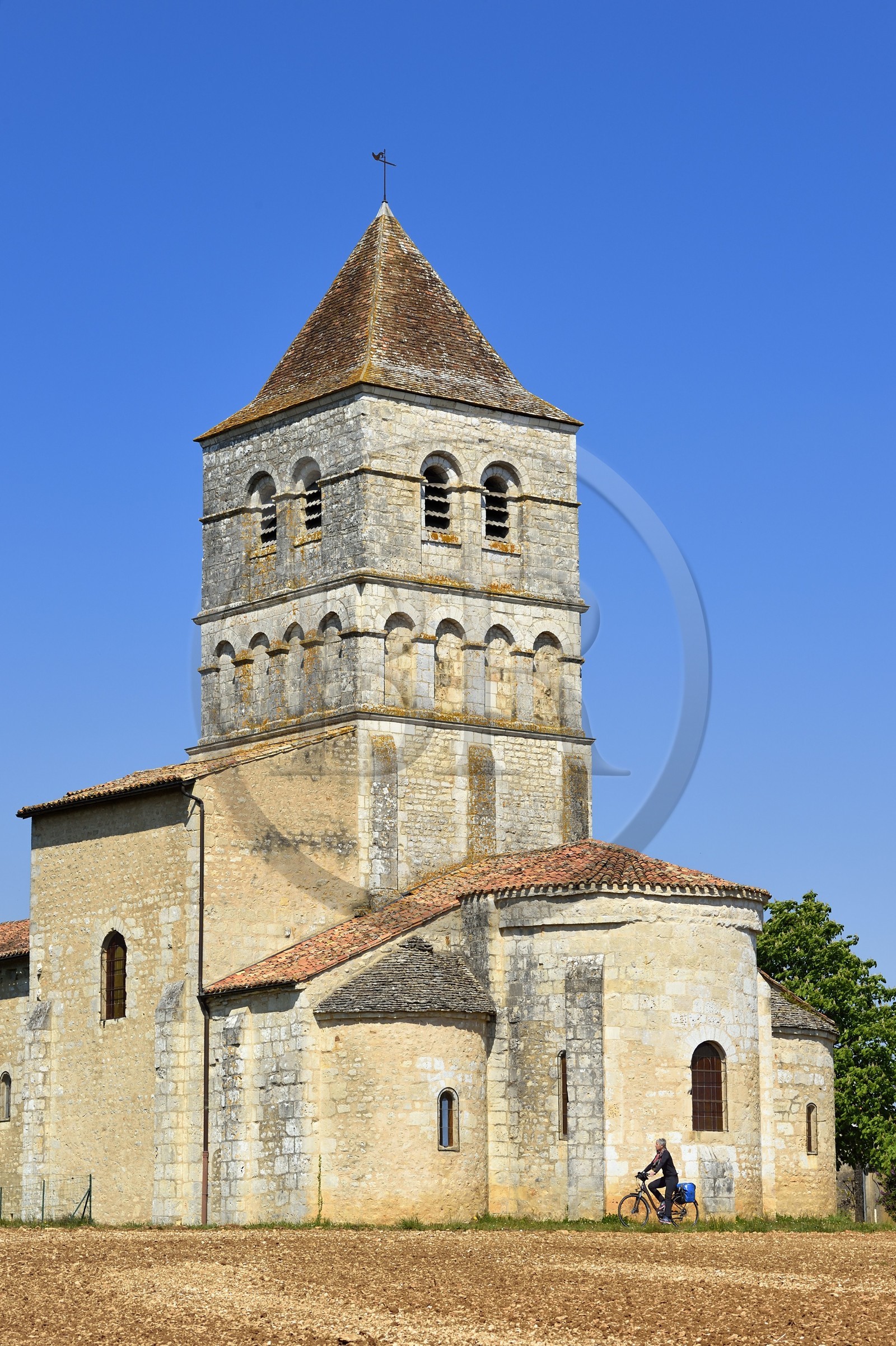 France, Dordogne (24), Périgord Vert, Javerlhac-et-la-Chapelle-Saint-Robert, cycliste faisant la véloroute La Flow Vélo devant le chevet de l'église romane XIIème siècle de La Chapelle-Saint-Robert, église de l'ancien prieuré fondé par un disciple du premier abbé de la Chaise-Dieu Robert de Turlande