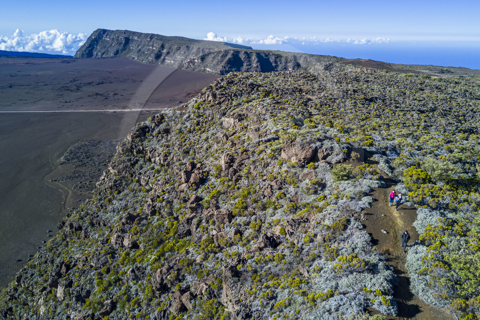 France, Ile de la Reunion, Parc National de la Réunion classé Patrimoine Mondial de l'UNESCO, sur les pentes du volcan de Piton de la Fournaise, randonneurs sur le sentier de l'oratoire Ste Thérèse au dessus de la Plaine des Sables que l'on aperçoit en contrebas (vue aérienne)