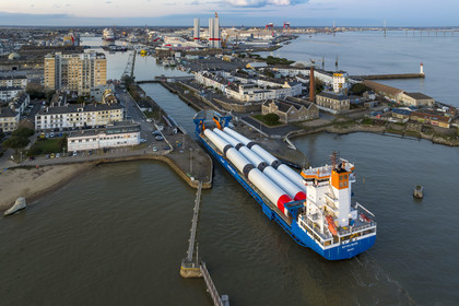 France, Loire Atlantique, Saint Nazaire, The General Cargo Rotra Mare transports sections of wind turbine masts and enters the port's wet dock (in the background) via the south lock, which was also the site of Operation Chariot launched in 1942 by the British (aerial view)