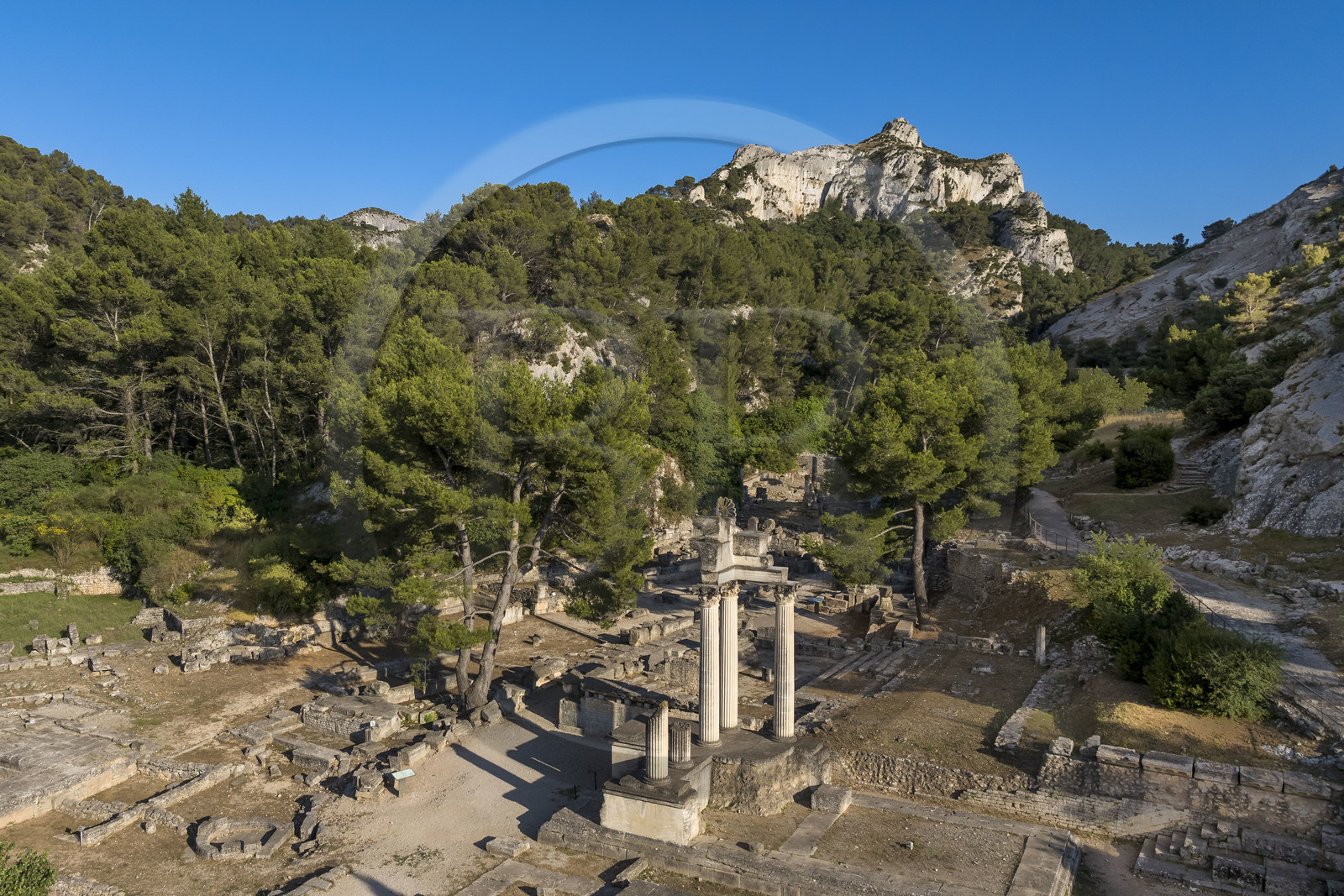 France, Bouches du Rhone, Regional Natural Park of the Alpilles, Saint Remy de Provence, site archéologique de Glanum at the foot of the Alpilles massif, reconstructed columns and entablature of the small twin temple of the first forum in the foreground (aerial view)