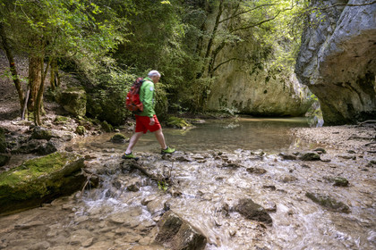 France, Vaucluse, Mont Ventoux Regional Natural Park, Monieux, Gorges de La Nesque, hiker crossing the Nesque river at the ford of the Saint-Michel chapel