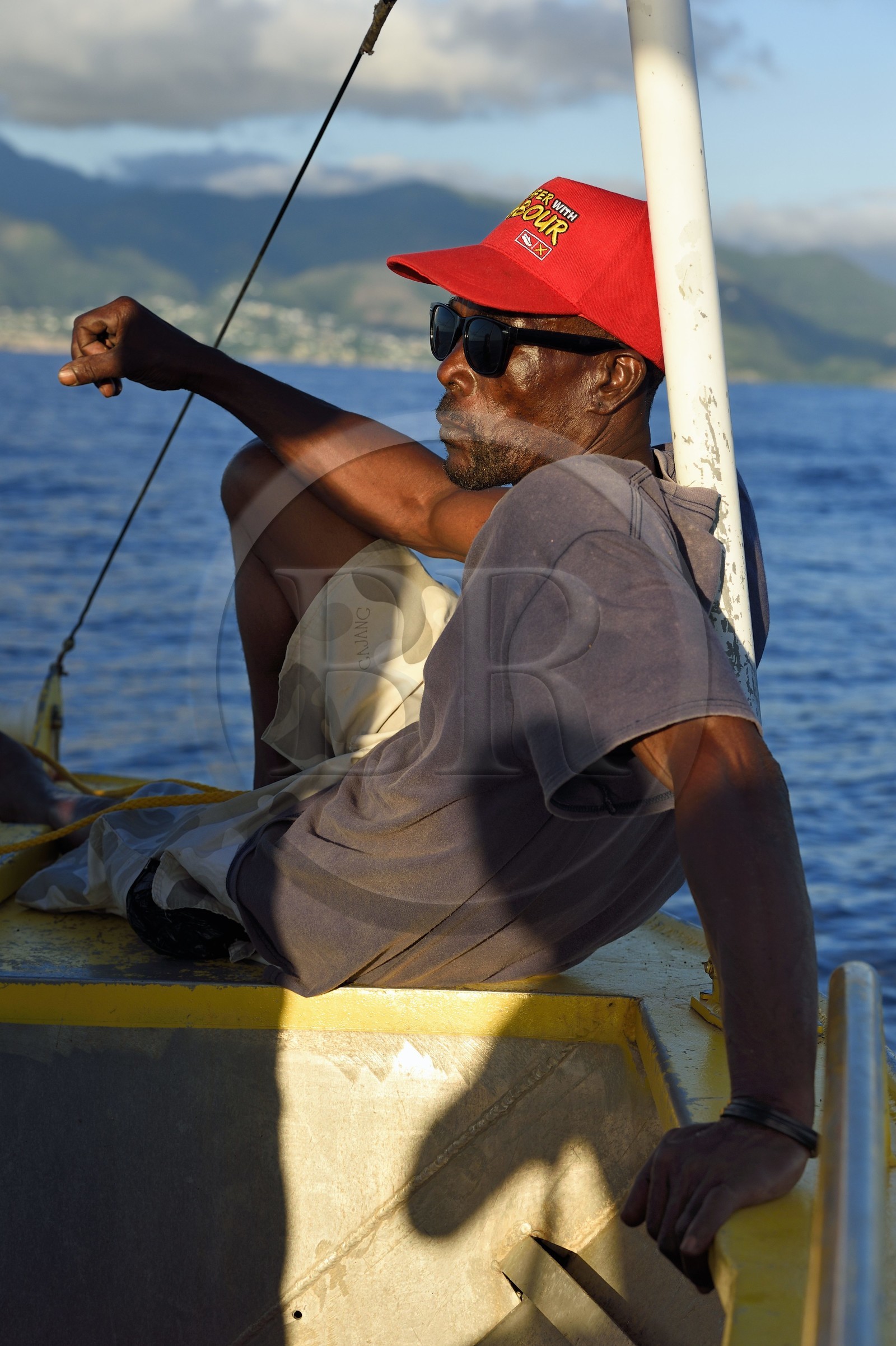 Caribbean, Dominica Island, Sylvester, second on the boat, observes the west coast north of Mero