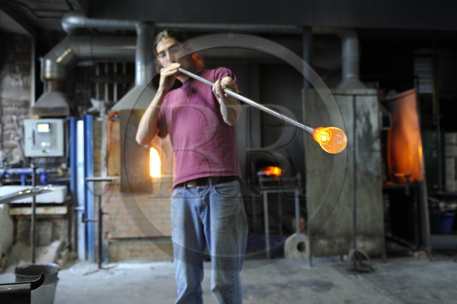 France, Moselle, Meisenthal, glassblower Thibaut at the Centre international d'Art verrier (CIAV) (international glass centre), making of a christmas bowl made of glass, turning and blowing the blowpipe at the same time