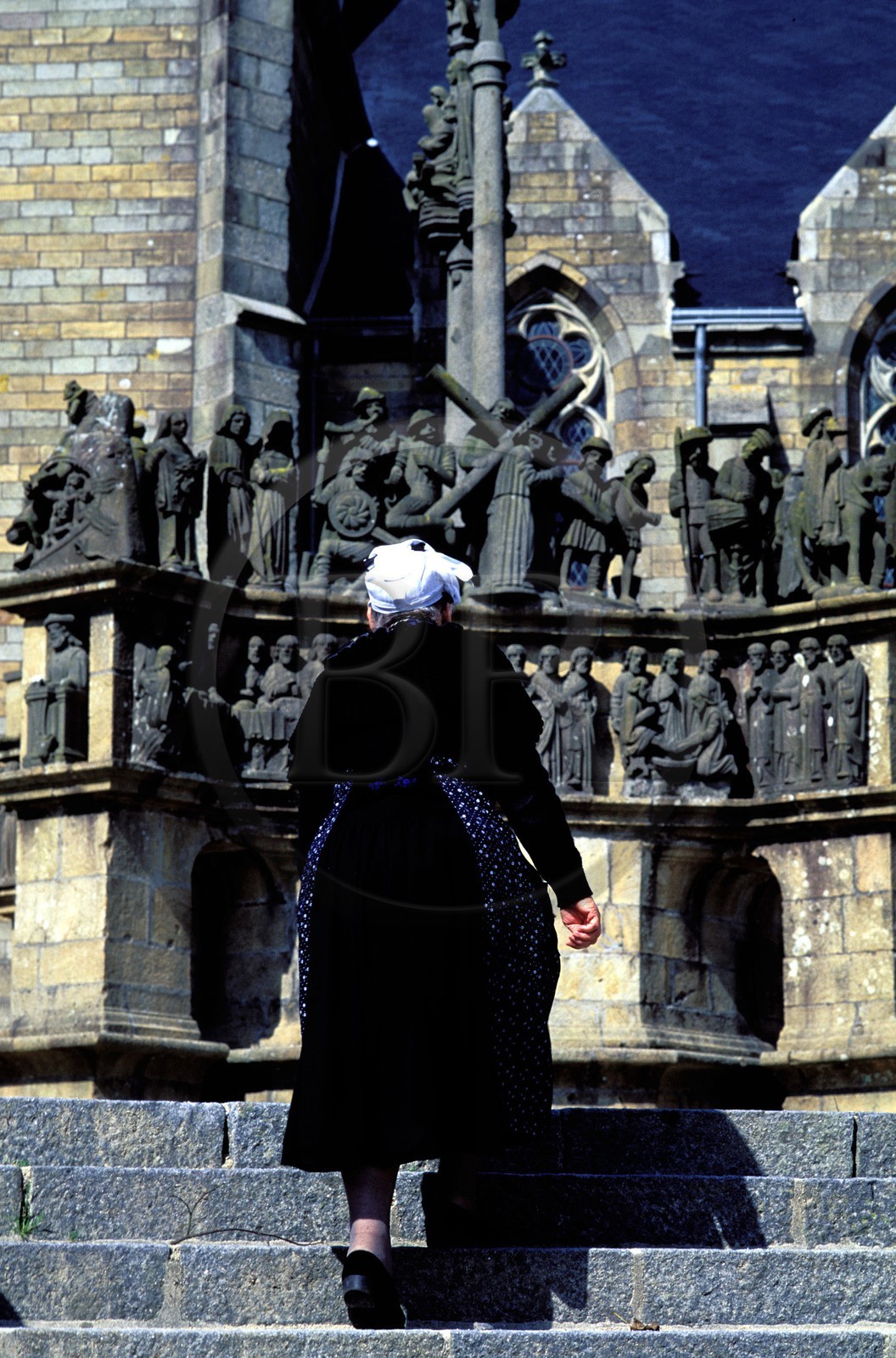 France, Finistère (29), femme en costume traditionnel devant le calvaire de Plougastel